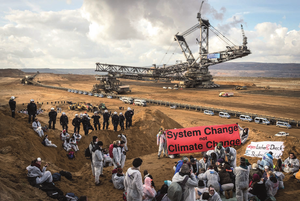 Photo manifestants à côté d'un puit de pétrole, slogan: system change, not climate change